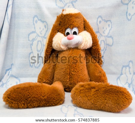 Toy, brown hare with long ears sitting on a blanket.