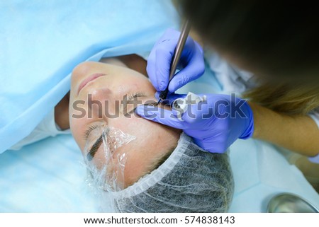 Young blonde woman professional, engaged in reconstruction work responsibly, eyebrows manual method performs procedure, using thinnest needle and maniples, draws most natural eyebrow, side by side on