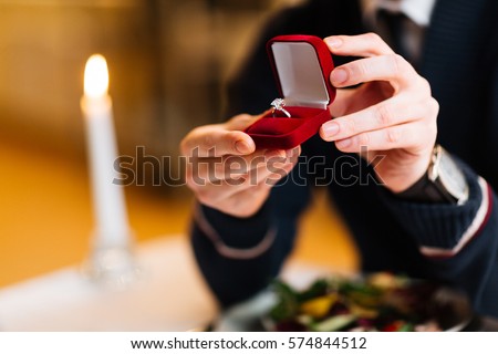Male hands with red velvet box containing engagement ring with brilliant Royalty-Free Stock Photo #574844512