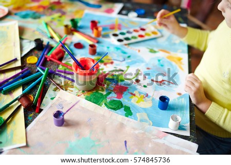 Picture drawn by gouache, objects for painting and little girl doing artwork