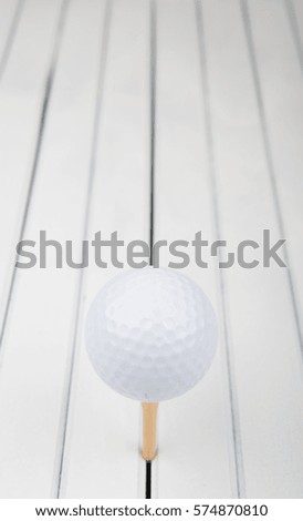 Golf ball and wood tee over wooden background