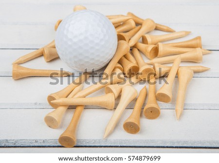 Golf ball and wood tee over wooden background