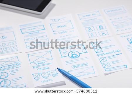 Designer working desk with wireframe sketches for mobile application, user interface design process