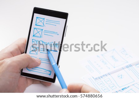Designer pointing on smartphone screen, responsive mobile user interface design 