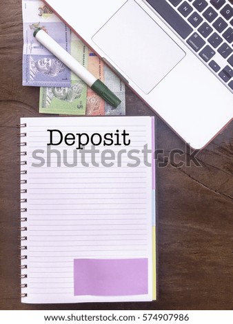 Deposit : Winspiration Typed Words for Banking and Finance on a handbook with note book, marker pen and Malaysian Ringgit notes. Vertical view, Vintage and classic mood on the top of the wooden table.
