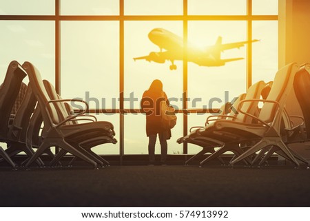 Tourist women seeing plane at passenger seat in Departure lounge for see Airplane, view from airport terminal.sun light in vintage color selective focus,transport and travel concept