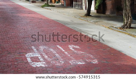 Diagonal composition of the contrast in a San Francisco street constructed of old brick cobblestones and concrete pavement, highlighted by faded inverted white lettering spelling out the word stop.