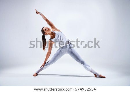 Sporty young woman doing yoga practice isolated on white background - concept of healthy life and natural balance between body and mental development Royalty-Free Stock Photo #574952554