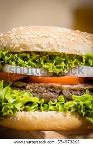 Delicious hamburger with vegetables in detail on wooden board