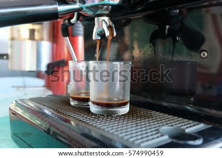 Porta filter espressomachine flow hot coffee to glass, Barista hand using a tamper to press ground coffee into a portafilter.