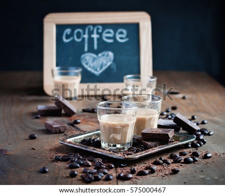 Shot glasses with homemade baileys, roasted coffee beans and chocolate, chalk board, heart drawing, love, selective focus, toned image