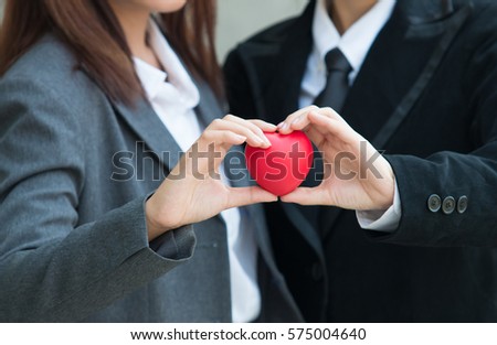 Woman in a business suit shows hands with heart. Royalty-Free Stock Photo #575004640
