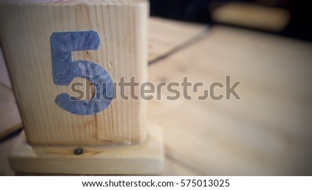 Number five on the brown table background at coffee shop or restaurant, number five rating