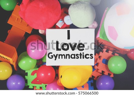 A lay flat happiness toys concept image of bunch of a mix child kids colorful ball toys fluffy kids puzzle foams a yellow rubber duck and a white canvas with a word I Love Gymnastics
