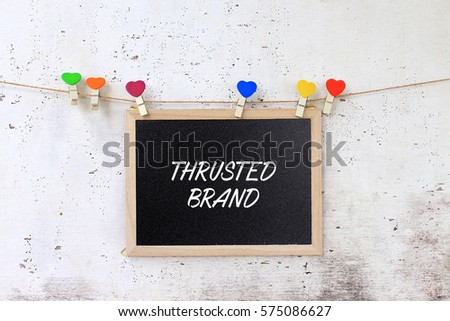 Thrusted Brand - concept words on blackboard with wooden clamps on rustic wooden background.