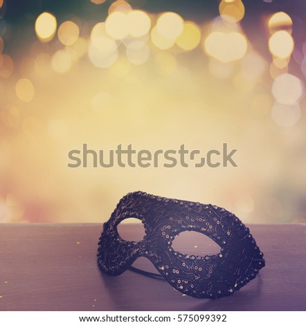 Mask on wooden table border isolated on bokeh background with copy space, retro toned