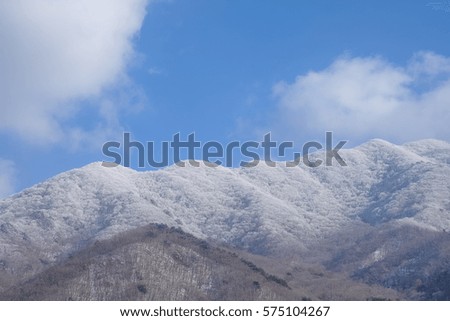 Beautiful snow landscape with mountains covered with snow and blue sky and white clouds above