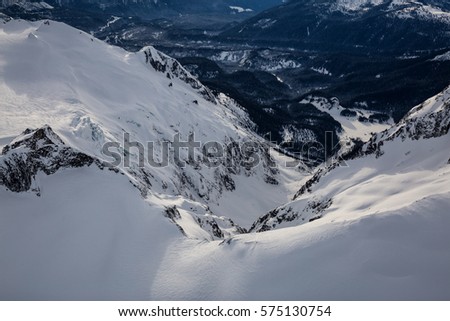 Aerial view looking down into a valley of a  cliff covered in snow. Picture taken at Mamquam Mountain, British Columbia, Canada.
