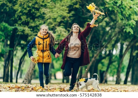 Two sisters holding hands while walking in the autumn park.
