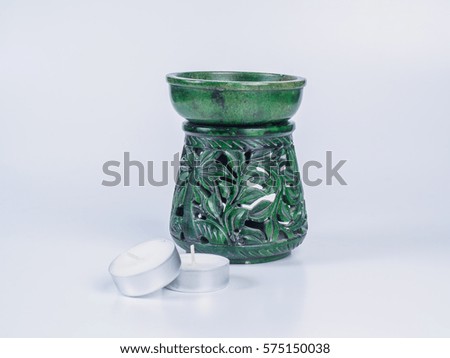 Picture of a green aroma lamp with two candles made of stone isolated on white background. Made of stone aroma lamp with floral ornaments.