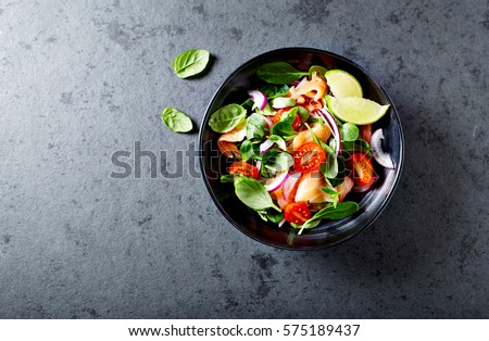Salmon Salad with spinach, cherry tomatoes, corn salad, baby spinach, fresh mint and basil. Home made food. Concept for a tasty and healthy meal. Dark stone background. Top view. Copy space. Royalty-Free Stock Photo #575189437