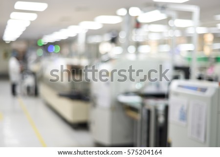 Electronics production plant creative abstract blur background with bokeh effect. Indoor photo of PCB assembly plant with SMT machine and workers.  Royalty-Free Stock Photo #575204164