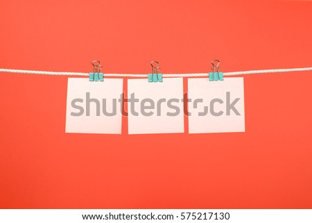 Blank pink paper sheets hanging on string over red background