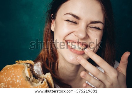 Woman laughing and eating a hamburger, hamburger and smile.