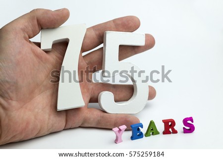 Hand holding number seventy-five on a white background.