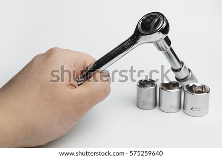 Hand holds a ratchet on a white background.