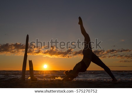 Harmonious landscape with a woman practicing yoga by the sea at sunset.