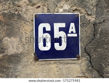 Vintage grunge square metal rusty plate of number of street address with number 65 closeup