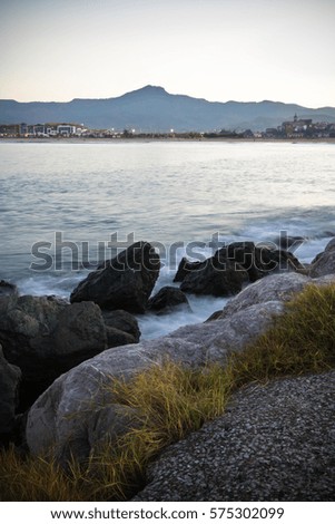 close up of rocks in atlantic ocean in long exposure, mountain three crowns in the back, pays basque, france