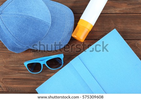 Vacation concept. Book, cap and sunscreen cream on wooden table