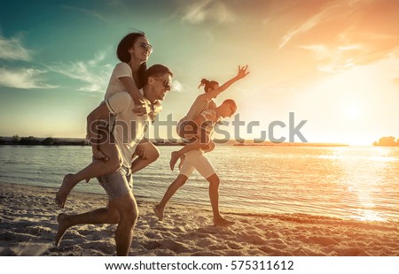 Friends fun on the beach under sunset sky with clouds at sunny day. Royalty-Free Stock Photo #575311612