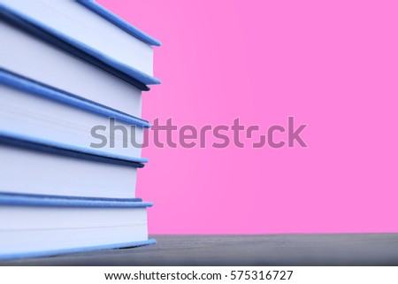 Books on wooden table and pink background