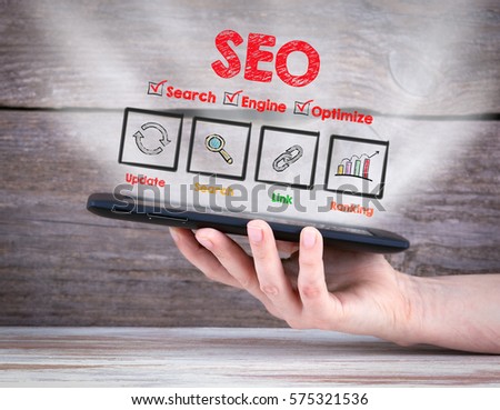 SEO concept. Tablet computer in the hand. Old wooden background