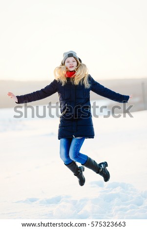 happy young girl on a snow-covered field and a red ball