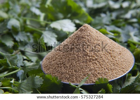 Close up of coriander powder in a bowl and coriander leaves
