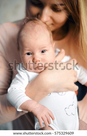 Young mother holds a newborn baby at home
