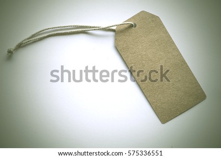 Blank tag tied with string. Price, gift, sale, address label. Dark style and soft focus.
