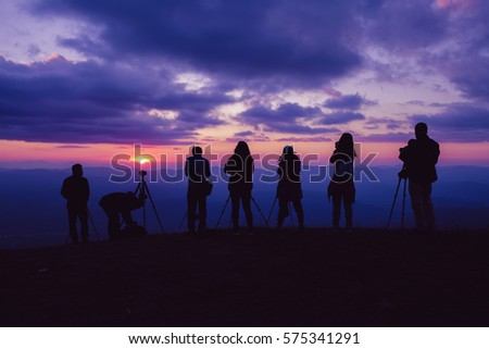 silhouette photographer group shooting a beautiful sunset with mountain in winter