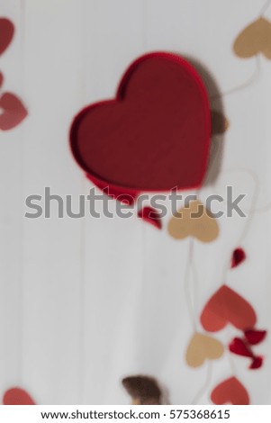 Blurry of paper heart and red heart silk box with shadow of wooden battens on white wooden table background on Valentine's Day times with copy space.