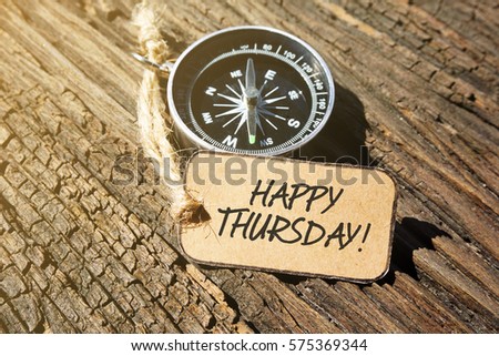 HAPPY THURSDAY! inscription written on paper tag, compass on old wooden background