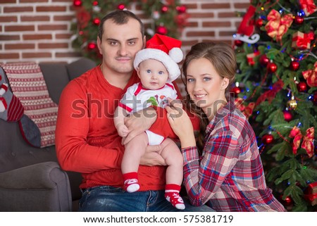 Happy family celebrating Christmas all together with cute baby daughter.Handsome father dad and beautiful mother mom  with cute baby in wonderful airy fairy dresses celebrating New Year.