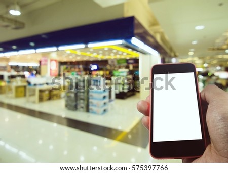 Smartphone in hand with blank screen isolated with space for copy on department store blurred background, business, technology and advertise concept, color tone effect.