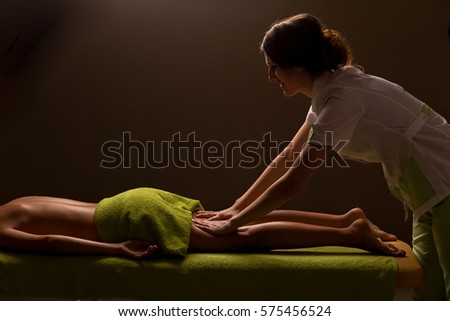 masseur doing leg massage in spa salon. low key photo