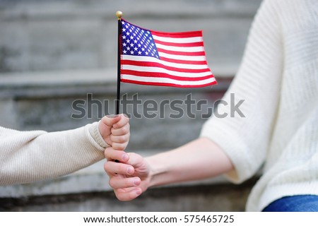 Young woman and little child holding american flag. Independence Day concept. Family together