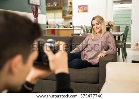 Point of view of a male photographer taking photos of a beautiful young woman at her home