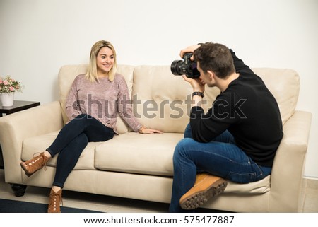 Male photographer using a dslr to take some photos of a woman at home